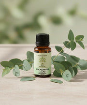 Bottle of Huile Essentielle Eucalyptus Globulus BIO | Purifie & rééquilibre la peau with eucalyptus leaves on a light surface