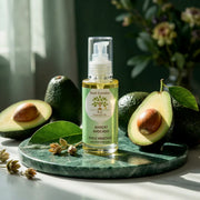 Bottle of Huile d'Avocat BIO – Nutrition Réparatrice with fresh avocados on a green marble surface in natural light
