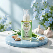 Bottle of Huile d'Ail BIO – Anti-Chute Capillaire garlic oil with garlic cloves and green garlic on blue marble tray.