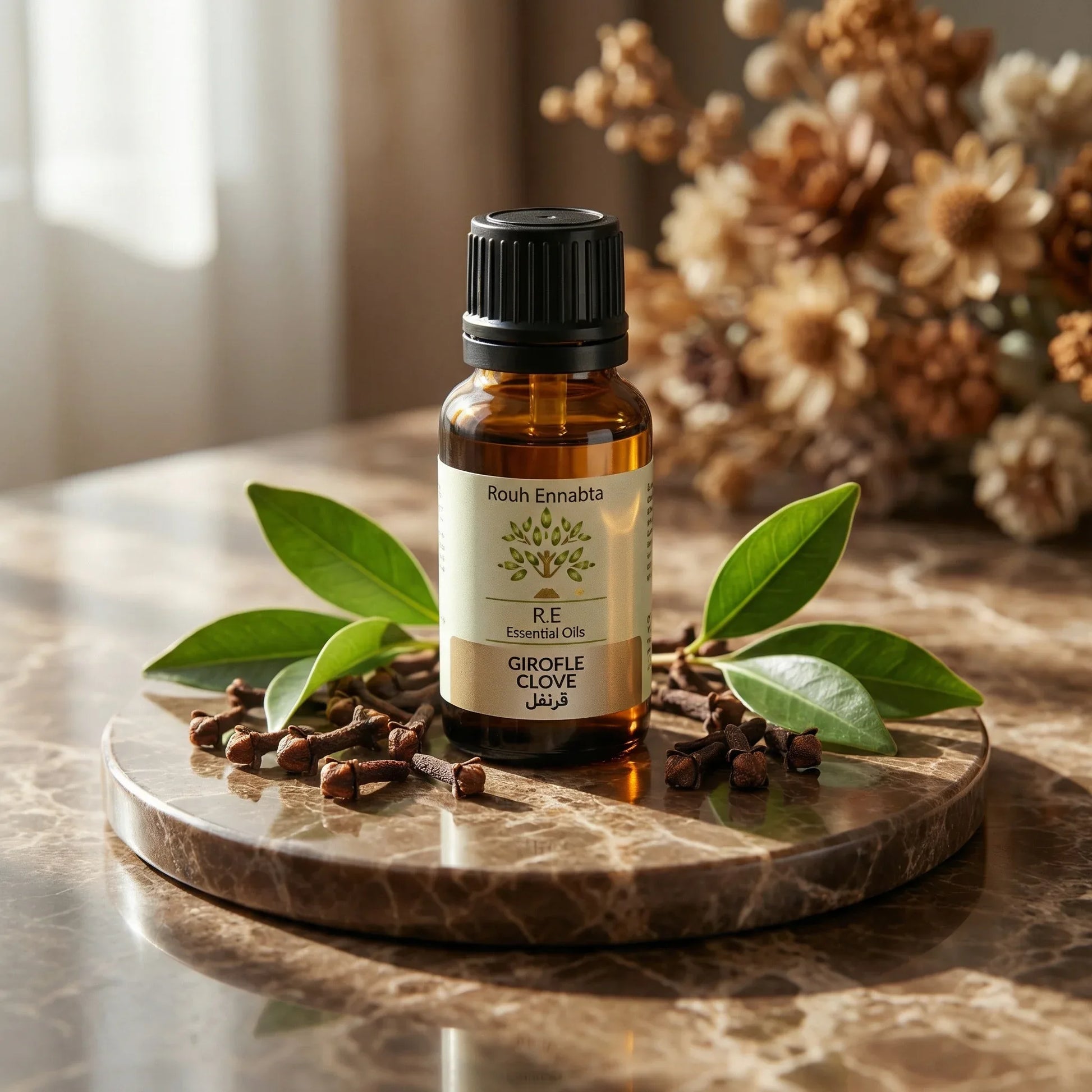 Brown glass bottle of Huile Essentielle Clou de Girofle BIO | Antiseptique & tonifiante with cloves and green leaves on marble tray.