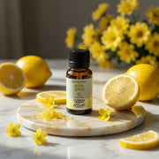 Huile Essentielle de Citron BIO – Éclat & Détox bottle surrounded by fresh lemon slices and yellow flowers on marble surface