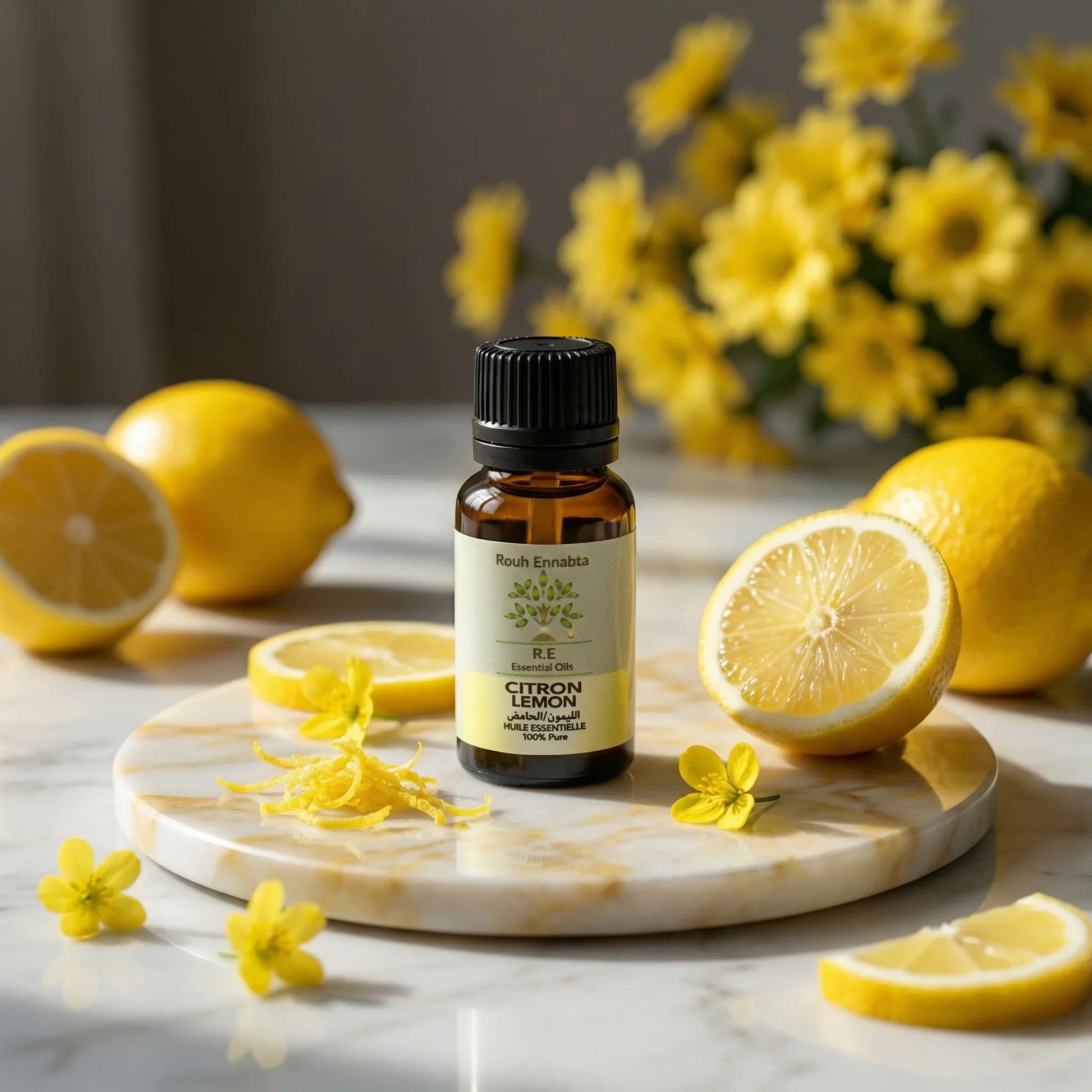 Huile Essentielle de Citron BIO – Éclat & Détox bottle surrounded by fresh lemon slices and yellow flowers on marble surface