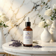 Brown dropper bottle of Huile de Lavande Pure | Apaise & répare la peau with lavender and white roses on marble table